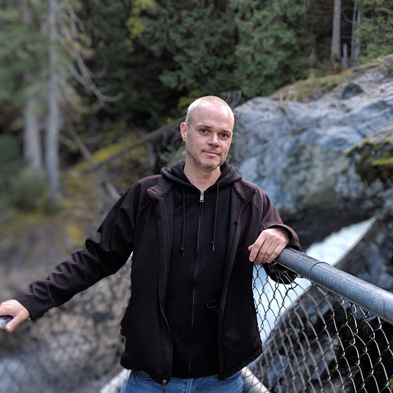 Scott Sutherland leaning on a fence in a forest