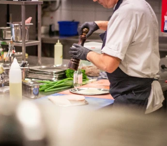 Chef grinding pepper in a kitchen